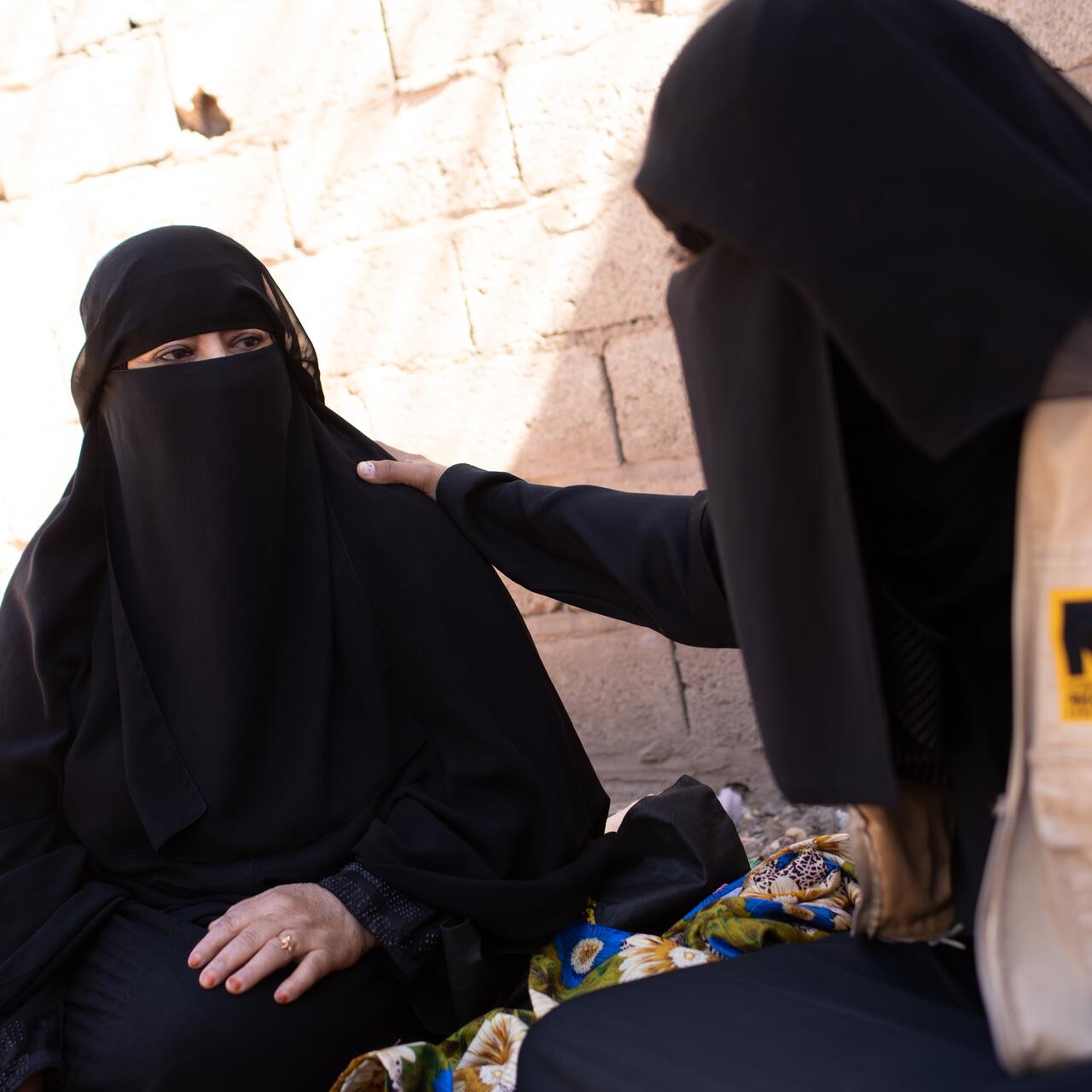 An IRC womens protection and empowerment staff member places her hand on a womans shoulder as they speak in Yemen.