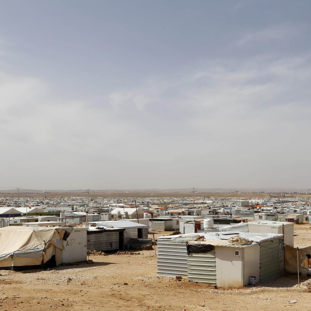 Zaatari refugee camp. The photo consists of many small tin houses on a flat desert landscape.