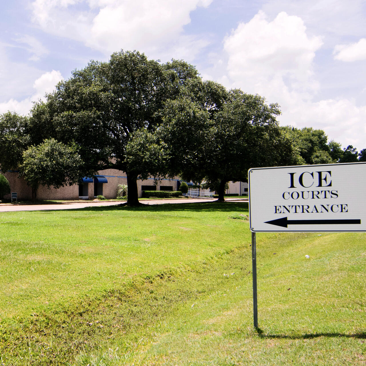 A lawn with a black and white sign that says "ICE Courts Entrance"