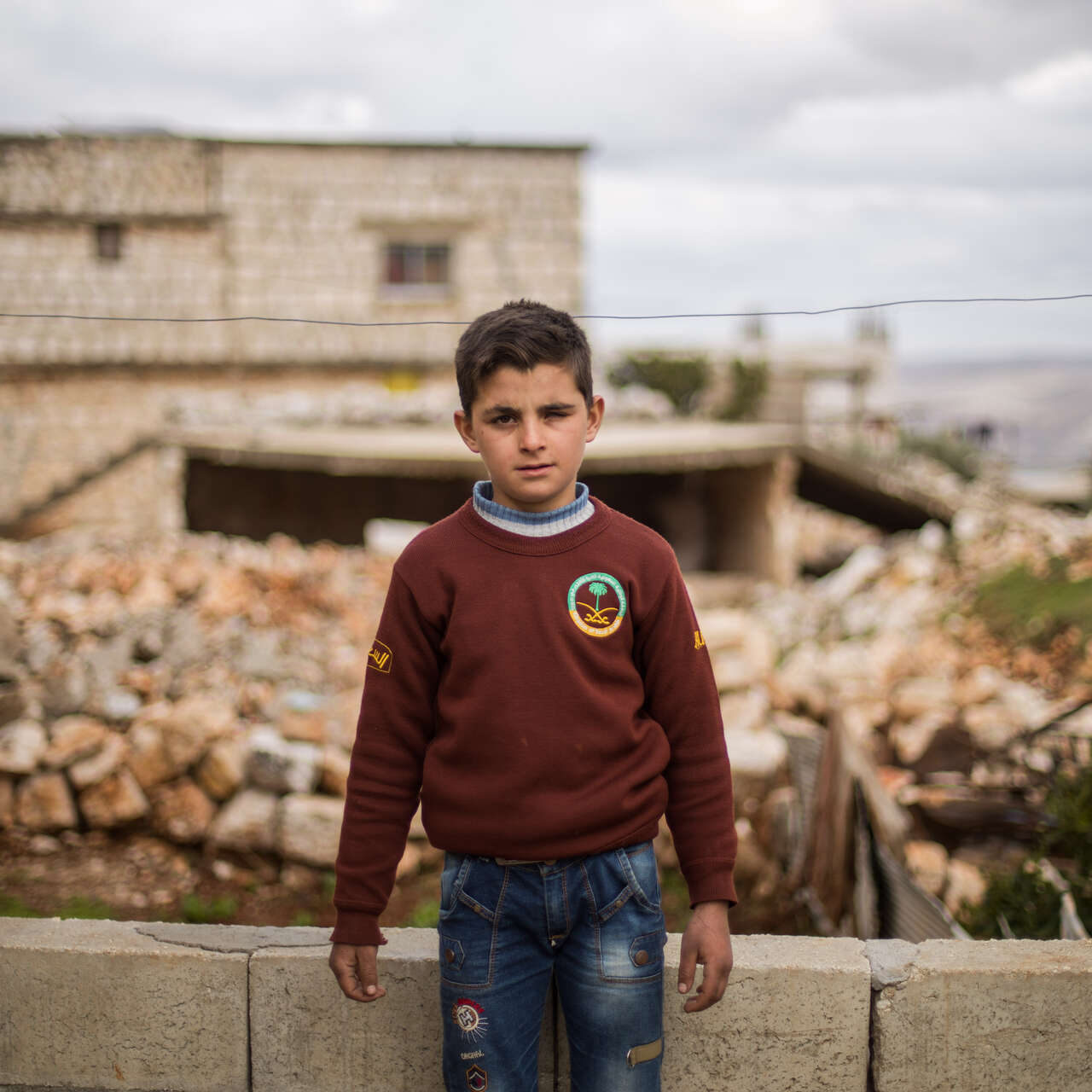Ten-year-old Ali stands in front of his family's home, which was damaged by an airstrike.