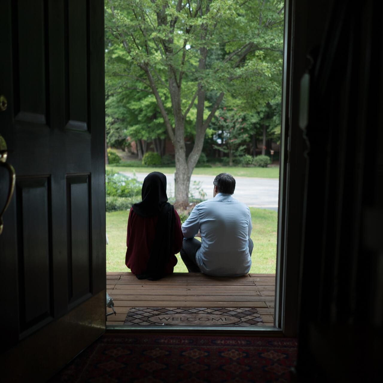 Afghan refugees Fatima, 19, and her father Abdul, 52, sit on the wooden front steps of their Virginia home looking out at the garden