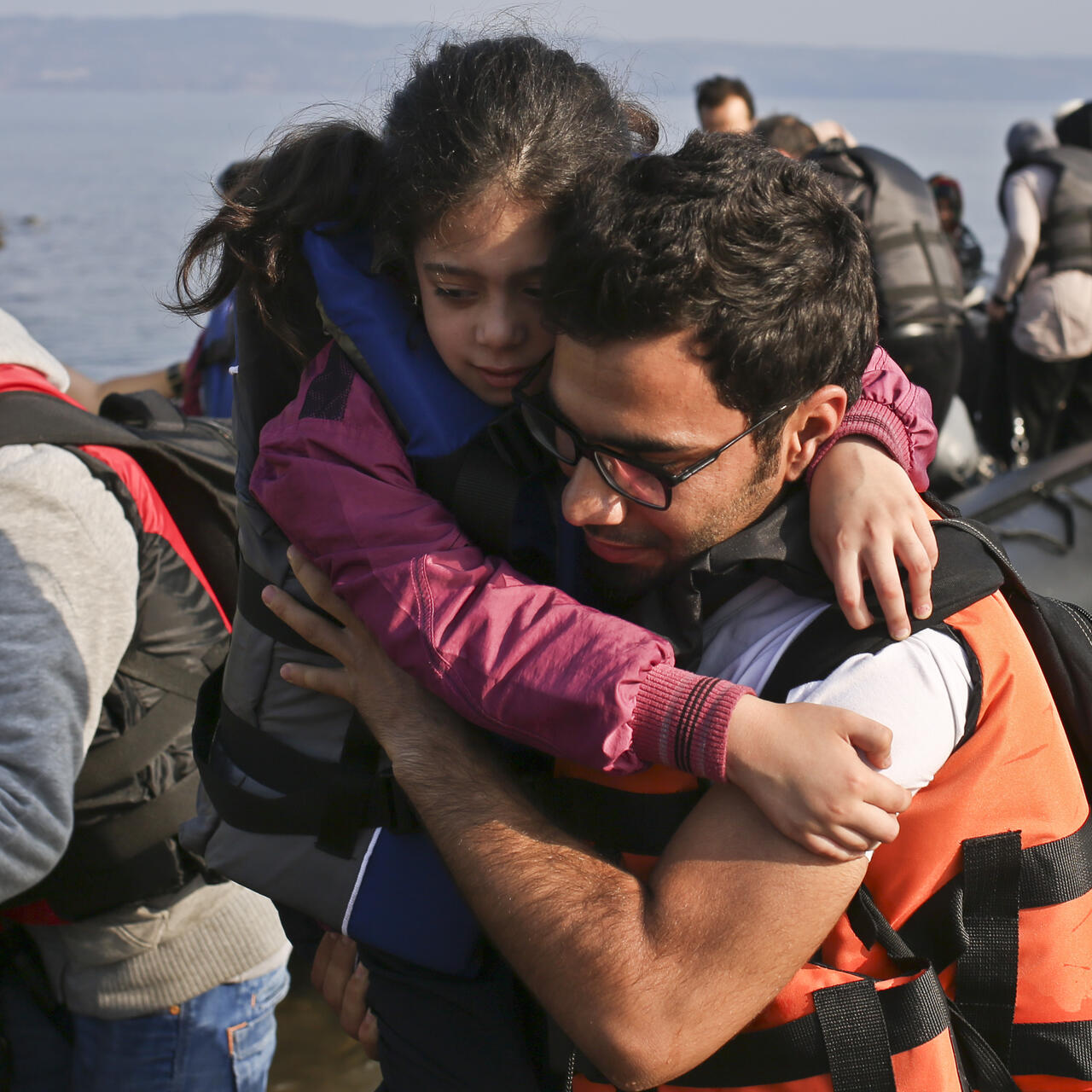 A Syrian man carries a little girl onto a Greek beach after arriving in a small boat from Turkey.
