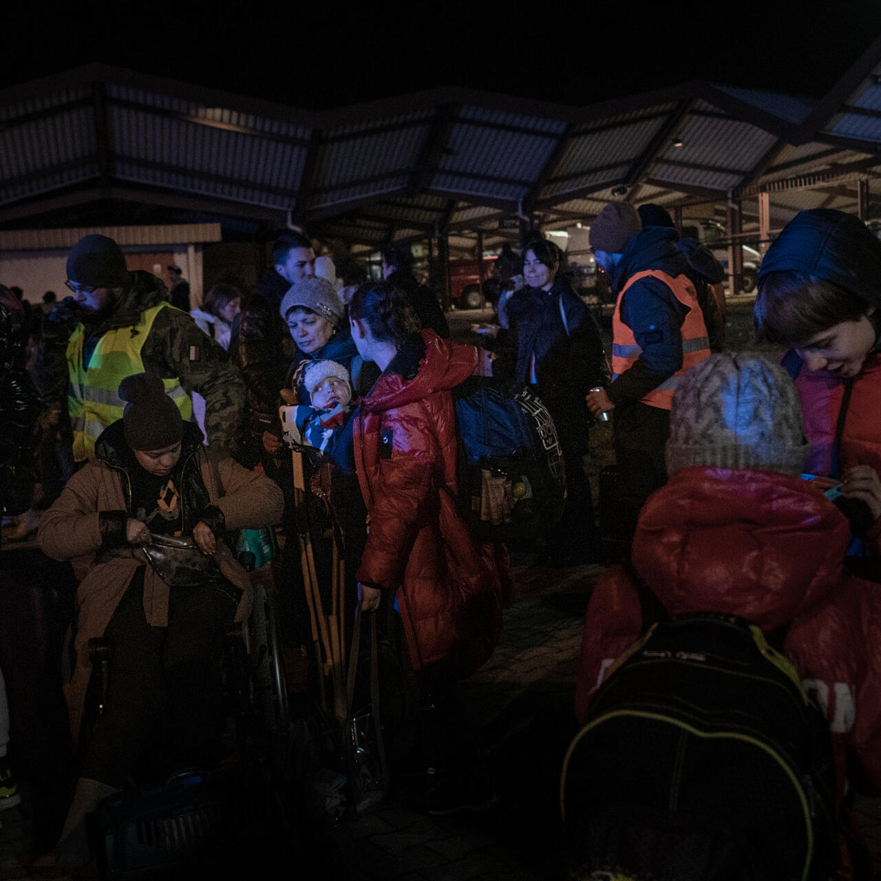 A group of refugees from Ukraine wait at a Polish train station at night after crossing the Ukraine-Poland border
