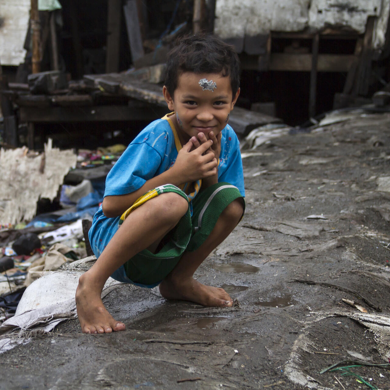 A child crouching in front of a building.