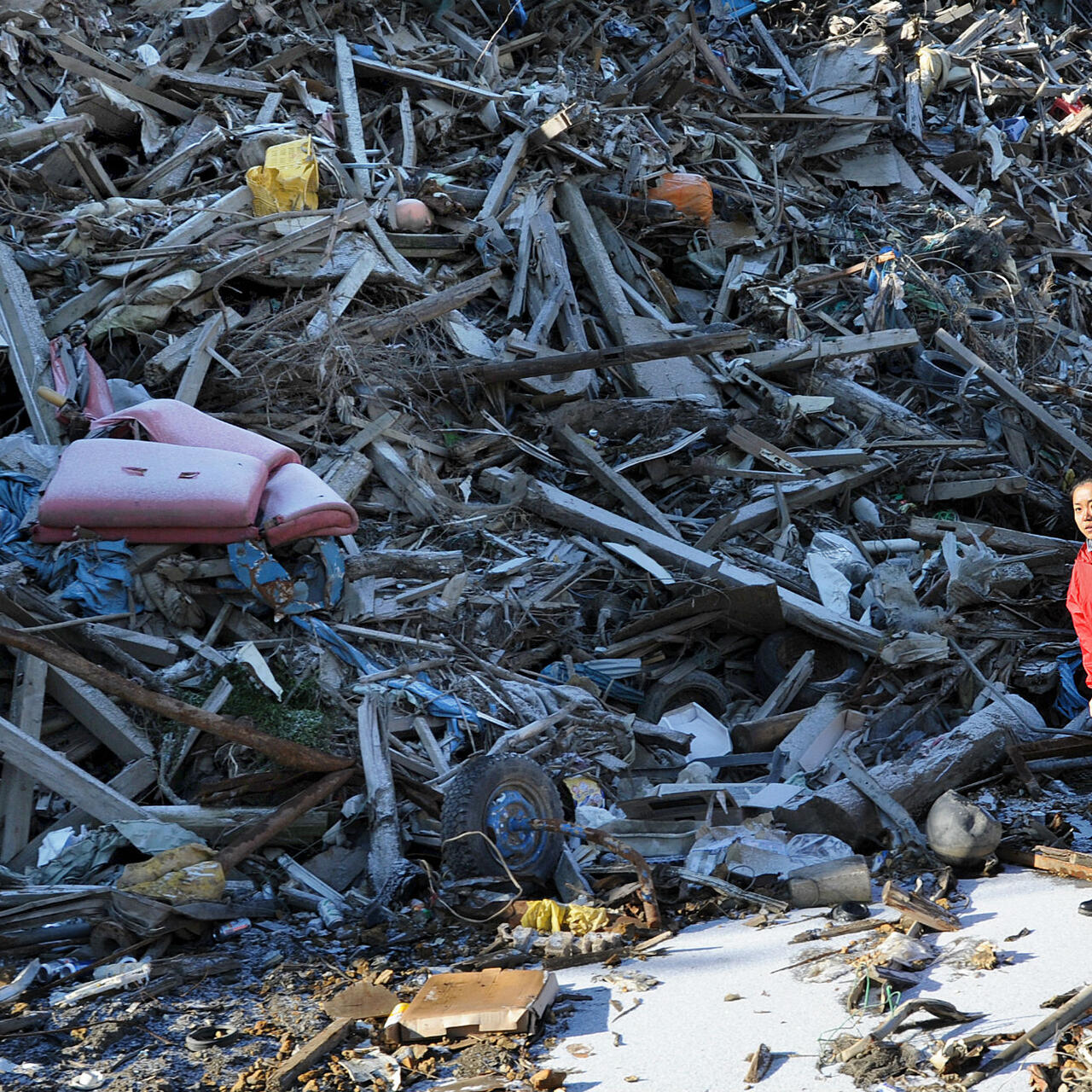 A Japanese aid worker walks through the debris of ruined buildings