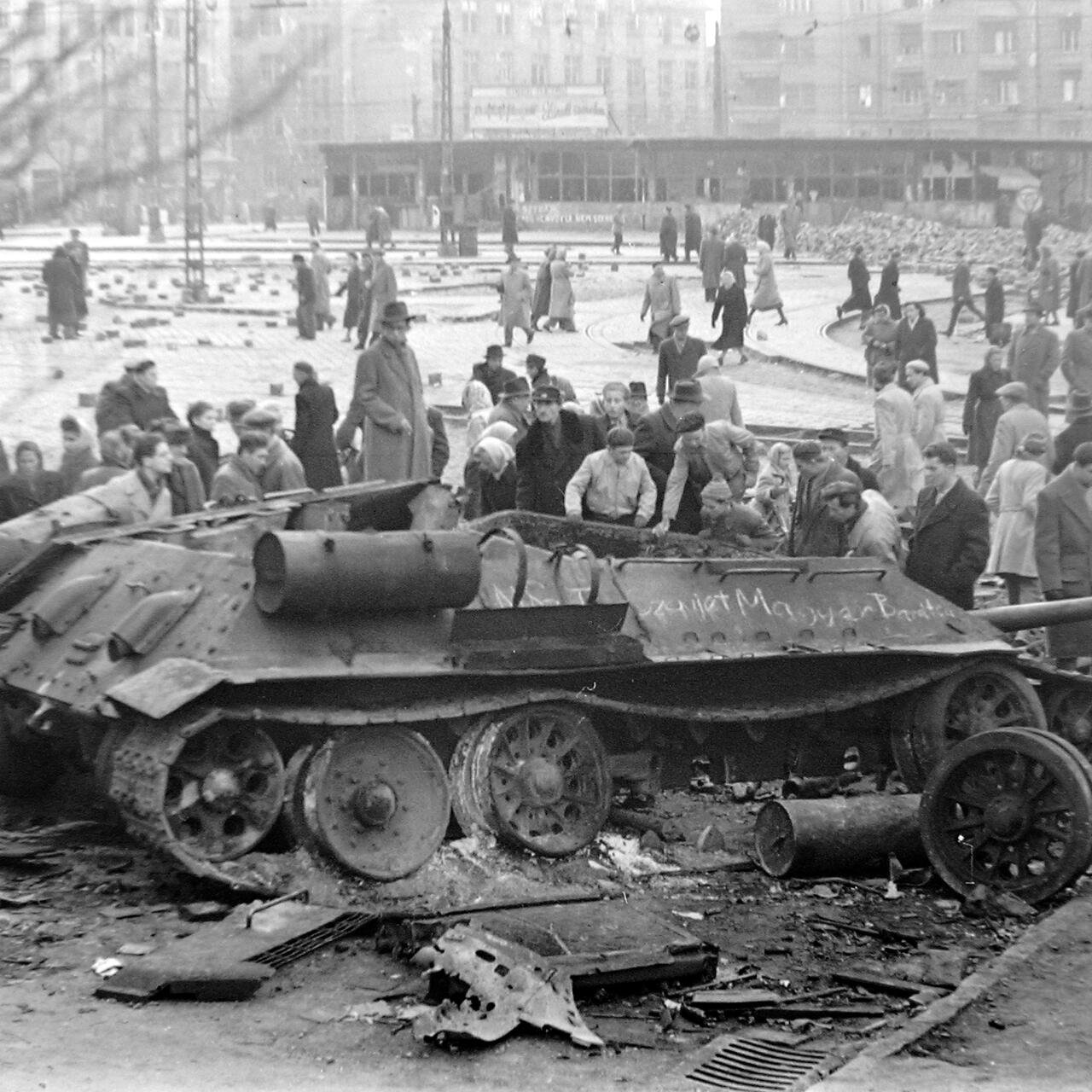A destroyed Soviet T-34-85 in Budapest is surrounded by civilians
