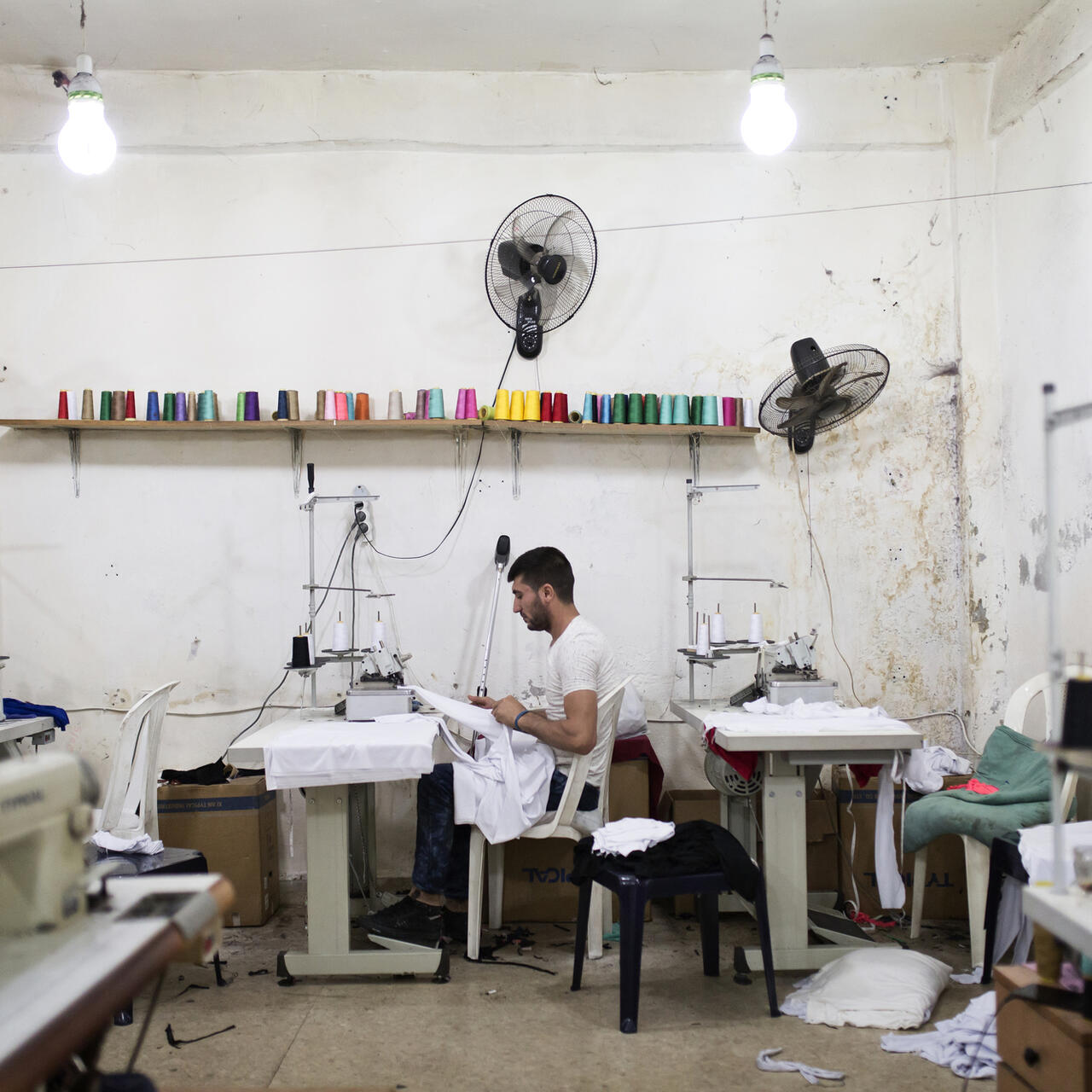Mohamed Saleh Ismail works at a sewing machine in a tailoring workshop where he is an apprentice.