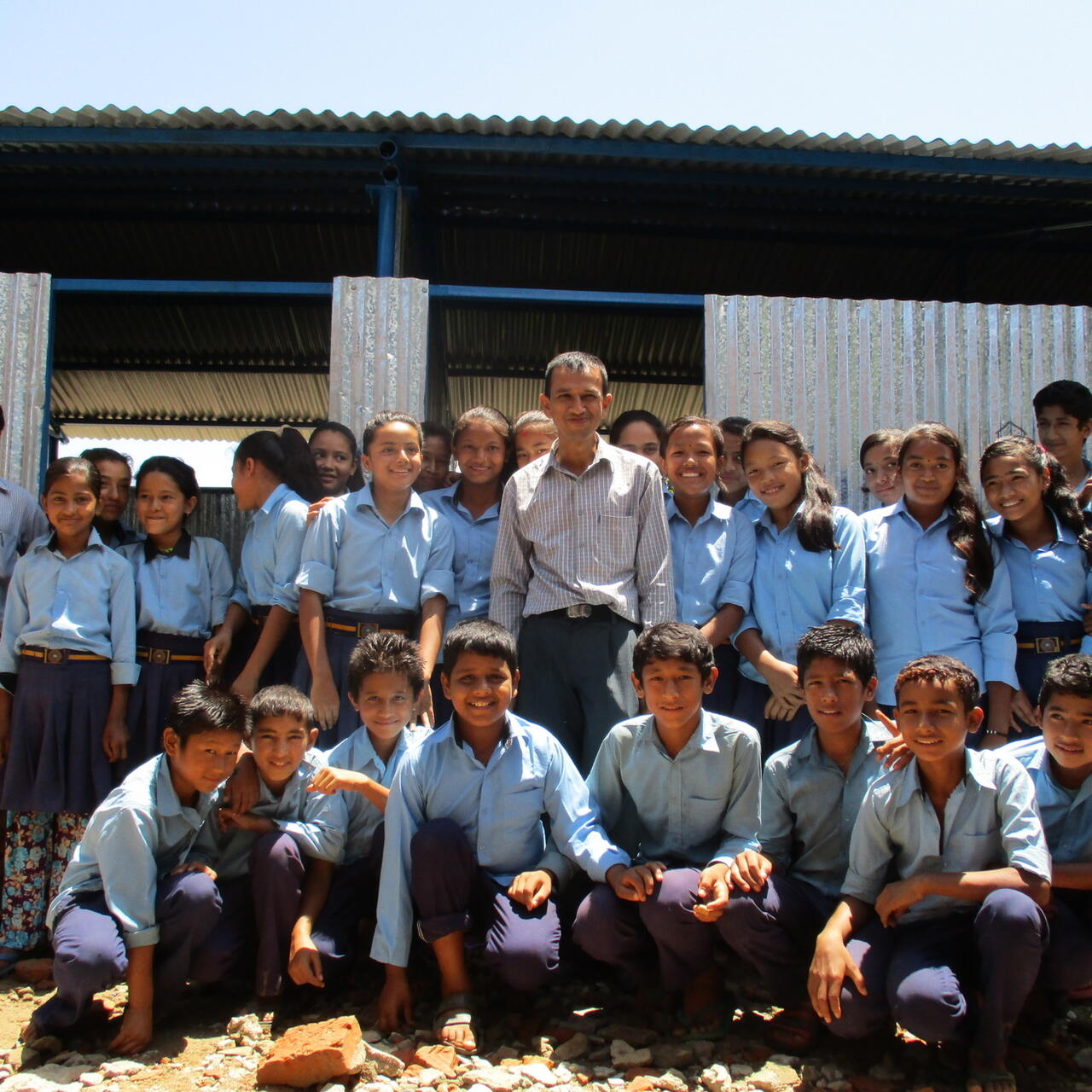 Secondary school principal Roshan Dhakal and some of his students outside a temporary learning centre.