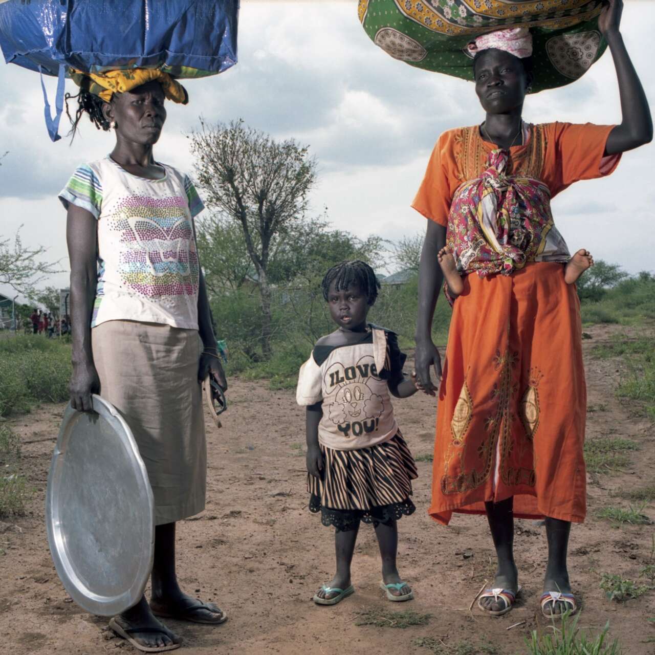 Women and children forced to flee their homes in South Sudan arrive at the Kenyan border on foot carrying their belongings.