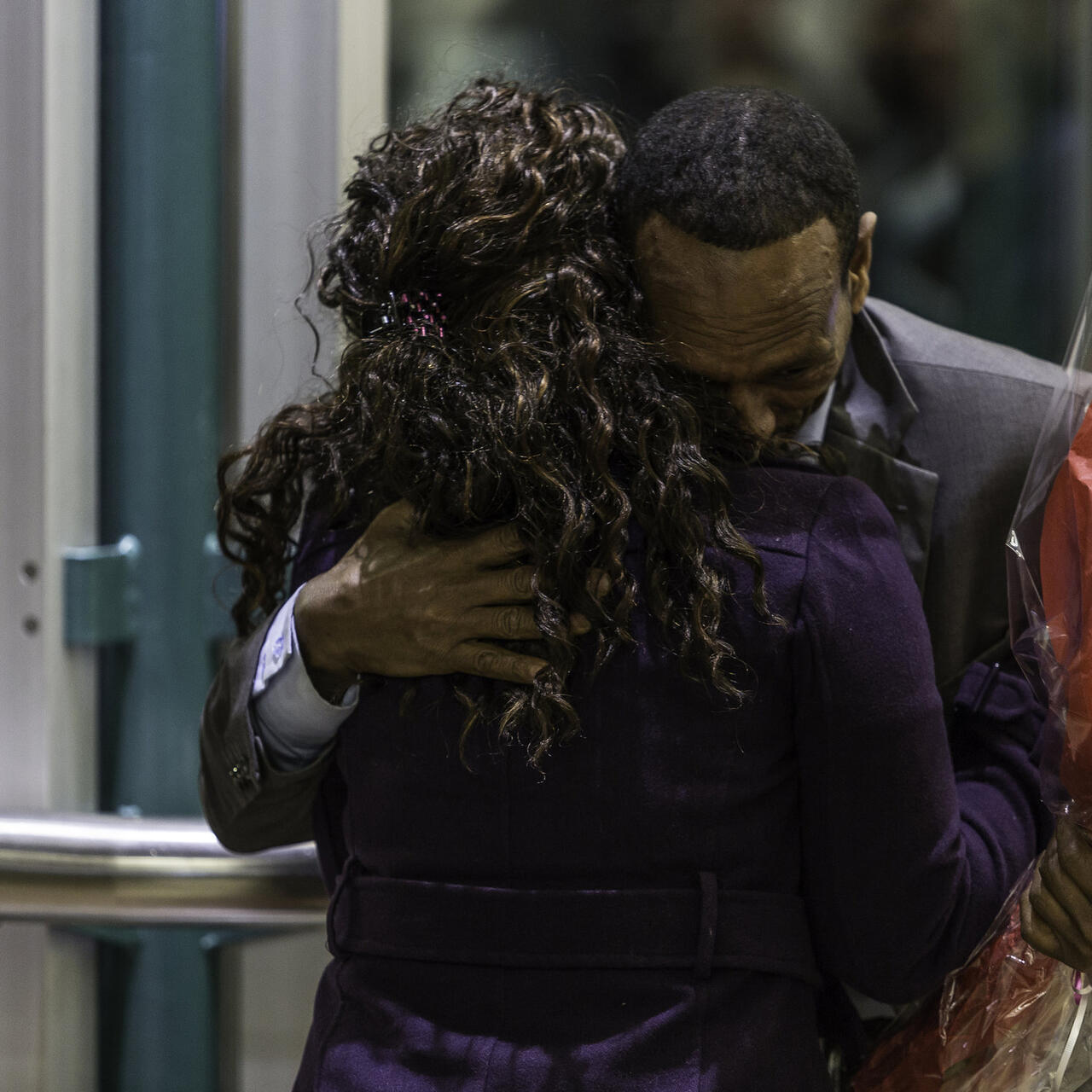 A Somali father holiding a bouquet of flowers hugs his daughter just after they are reunited in Seattle's SeaTac airport