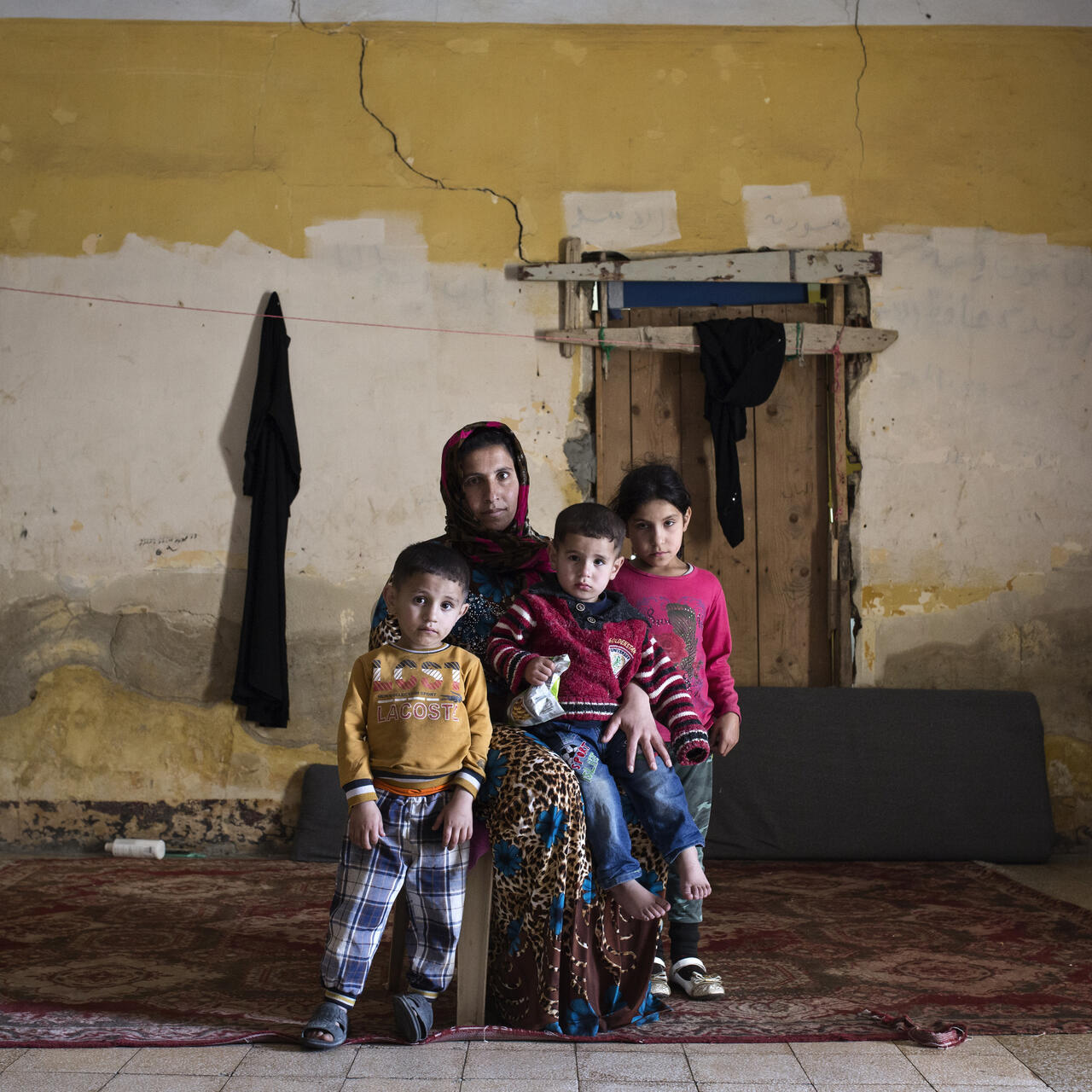 A Syrian mother and three children sit amid rubble in an abandoned building where they live as refugees in Lebanon.