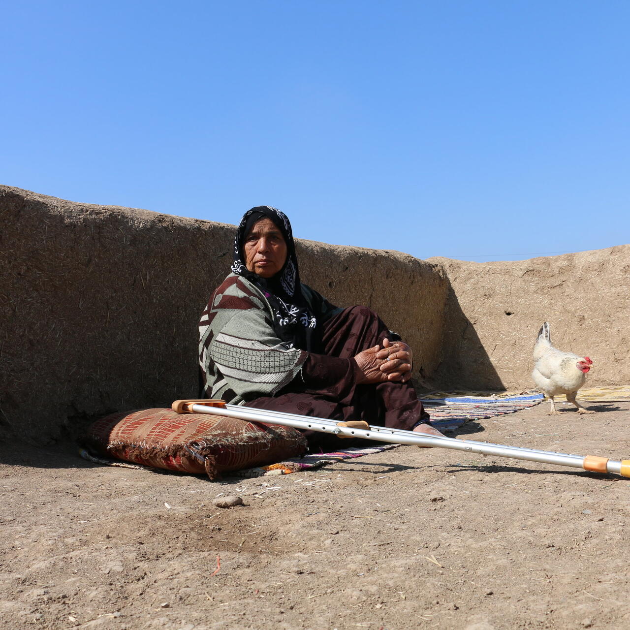 Miriam sits on a mat outside her home in Syria to get fresh air.