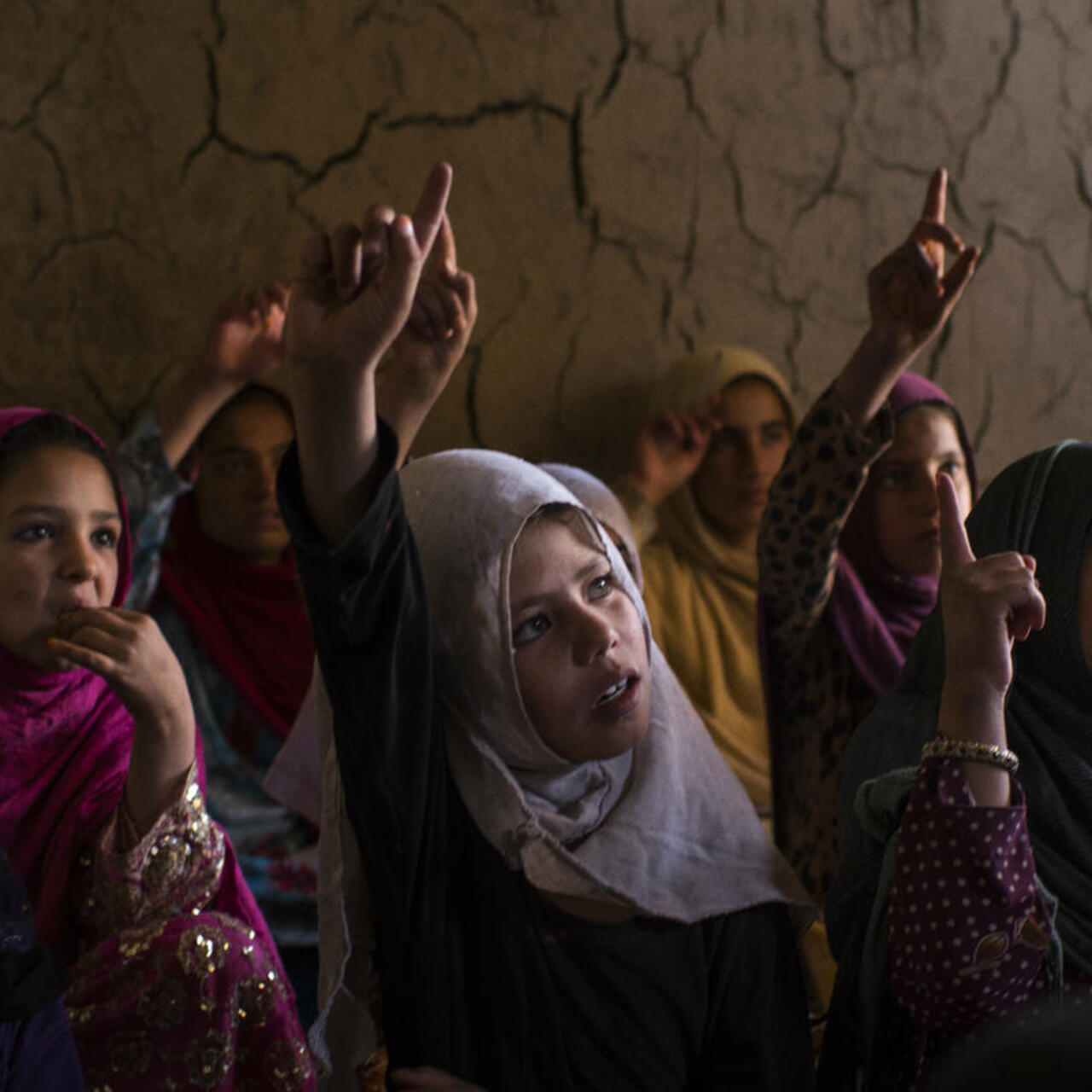 A group of school girls raise their hands