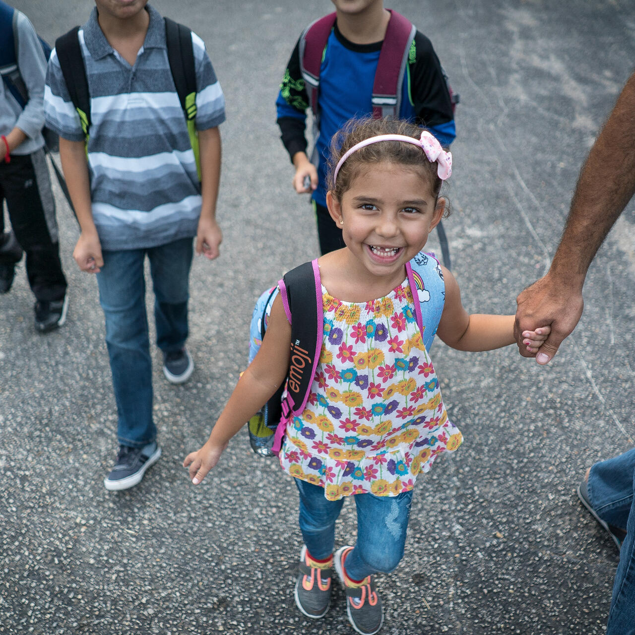 Jori holds her father's hand while walking to school