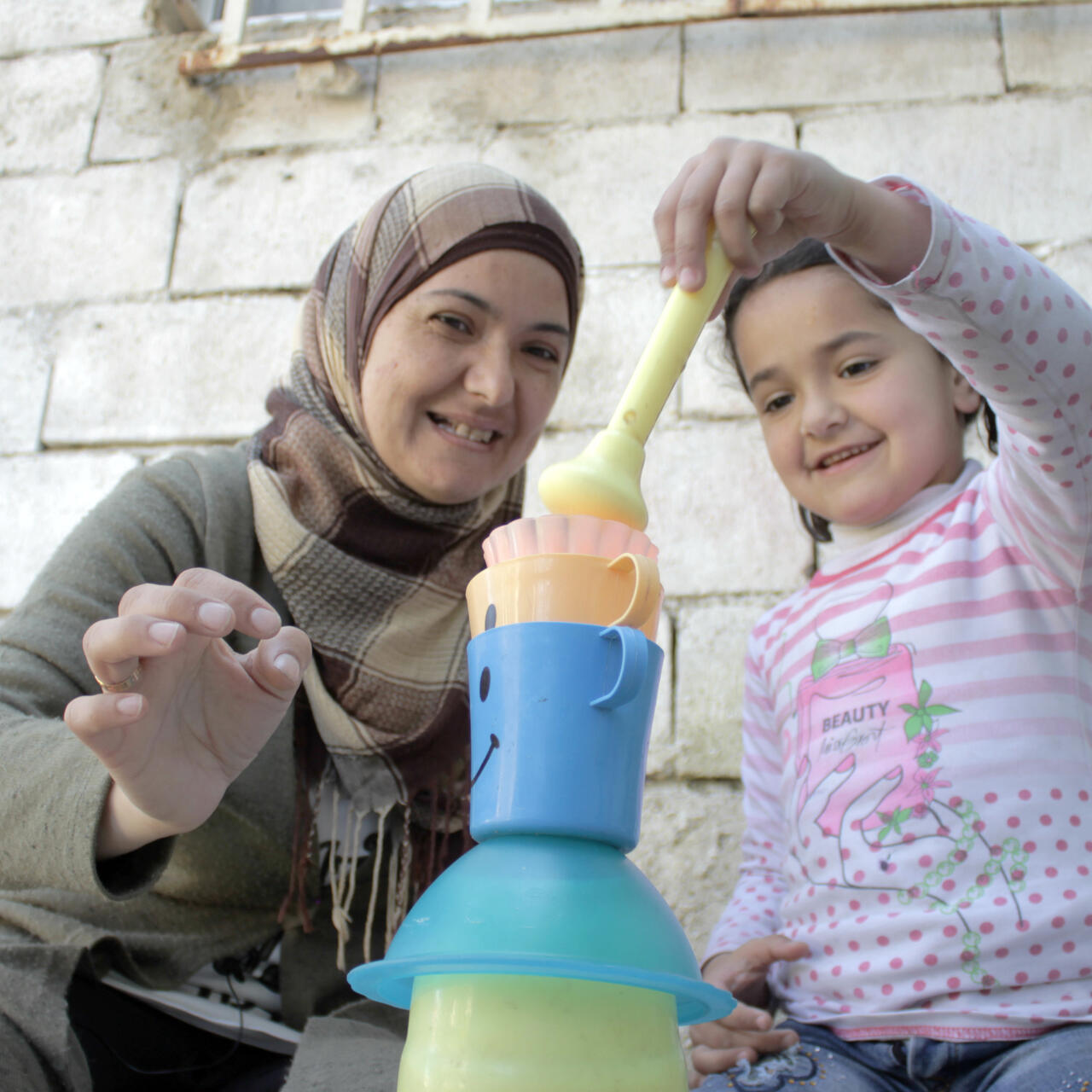 Ahlam and Sadal stack plastic cups as part of a Vroom activity