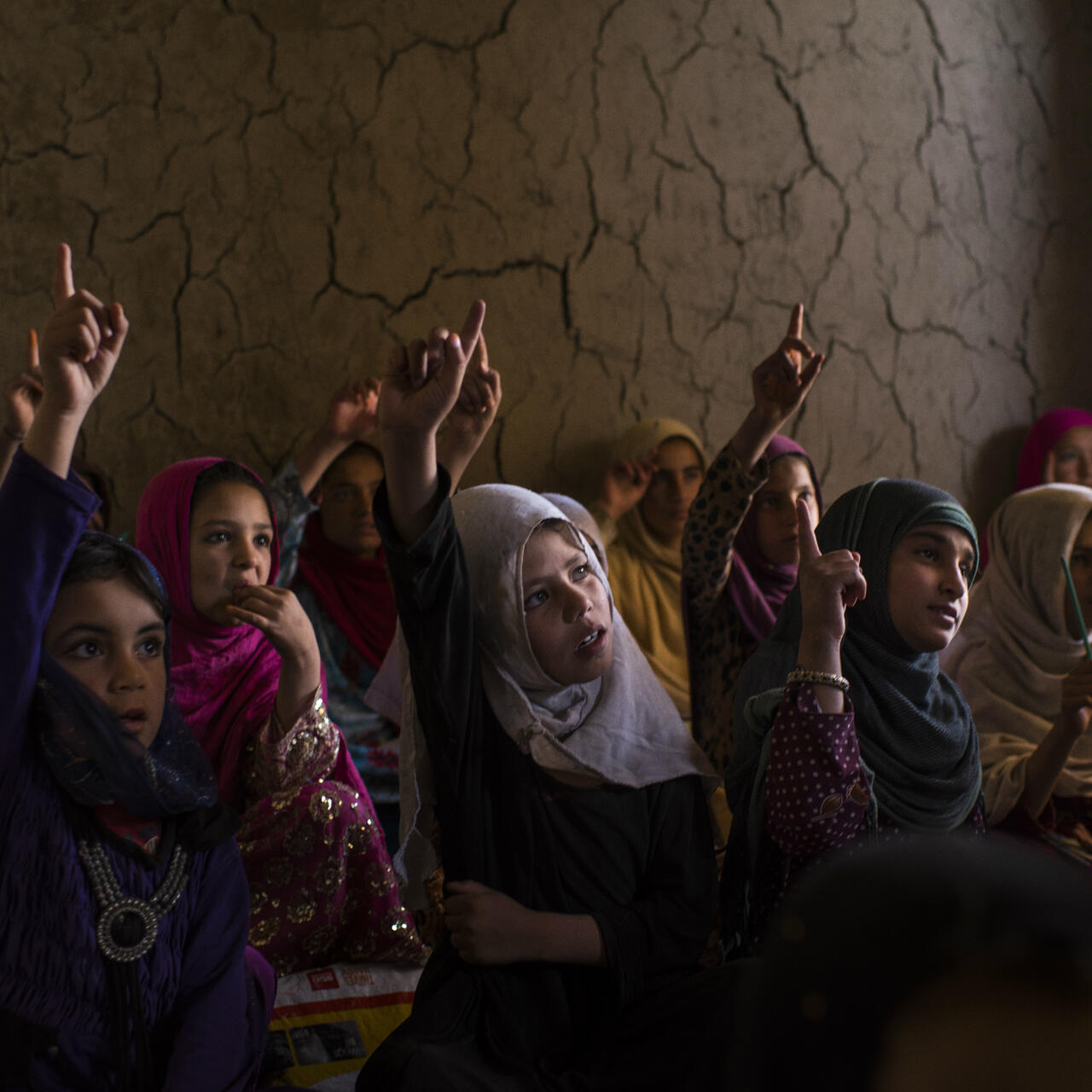 Afghan girls raise their hands in class