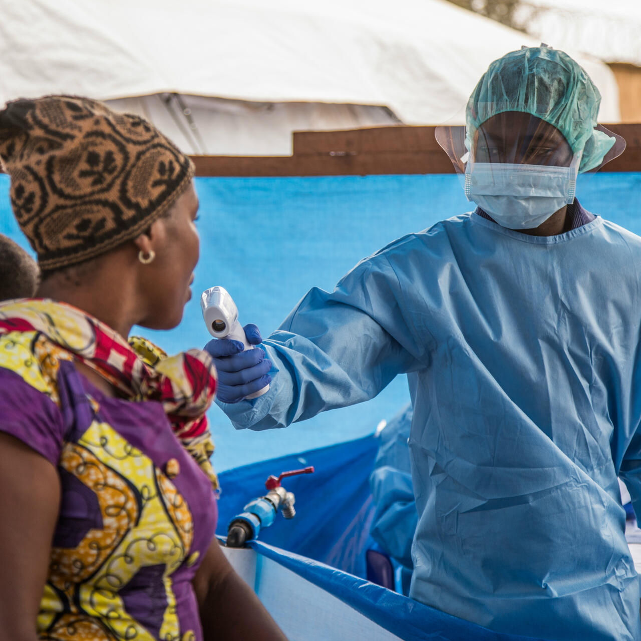 A health workers uses a scanner to screen a woman and baby for signs of Ebola