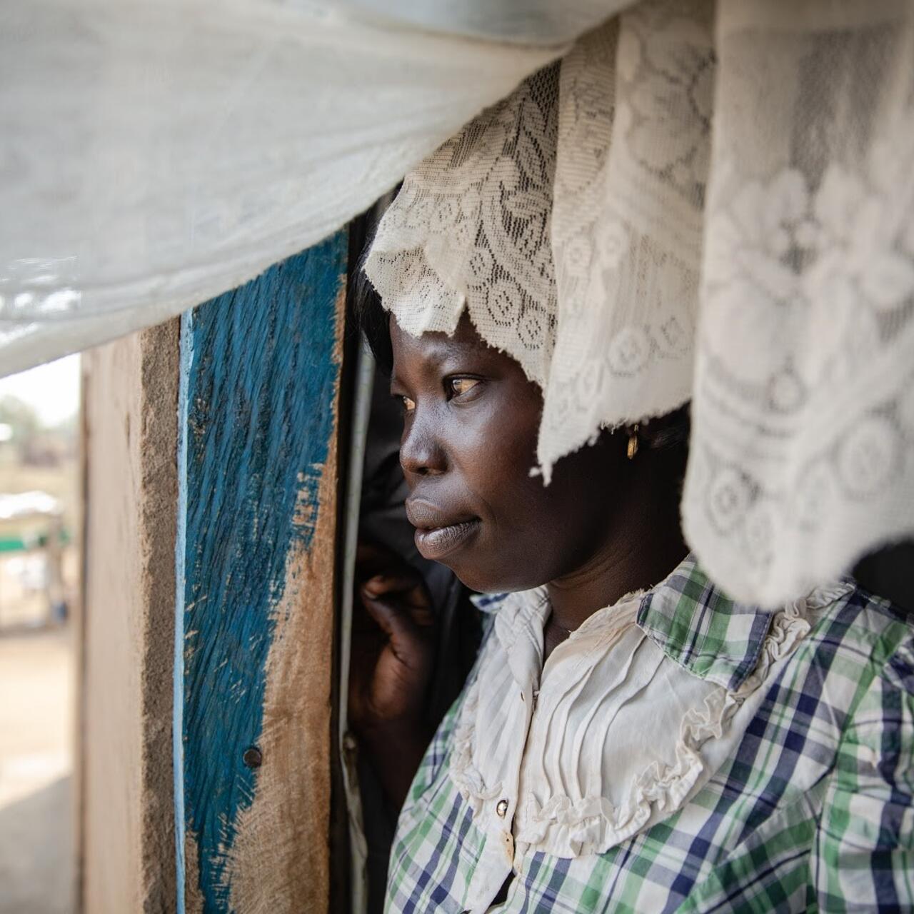 Foni Grace, an women’s rights activist, who is supported by the IRC looks out of her home in Bidi Bidi Camp in Uganda. IRC staff are now supporting her remotely via the phone.
