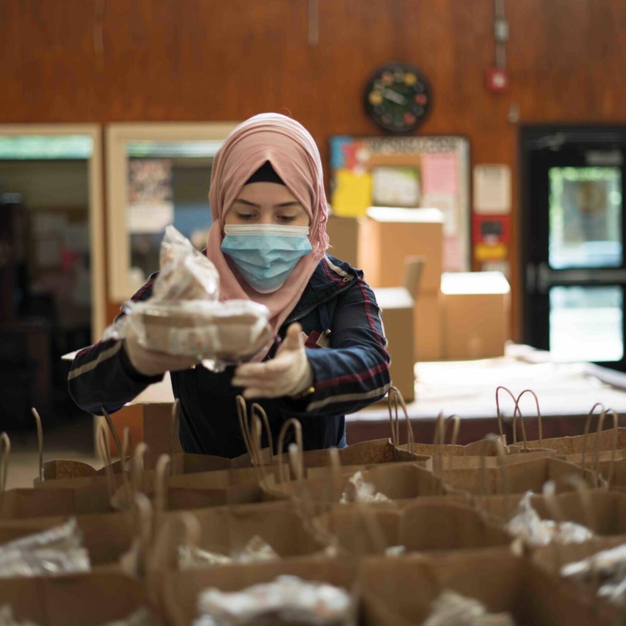 Refugee Rania Abou from Damascus, Syria distributes meals to people experiencing food insecurity in New Jersey, USA during the COVID-19 pandemic.