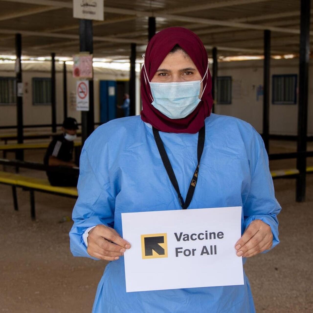 IRC senior health officer holding a sign saying "Vaccines for All"