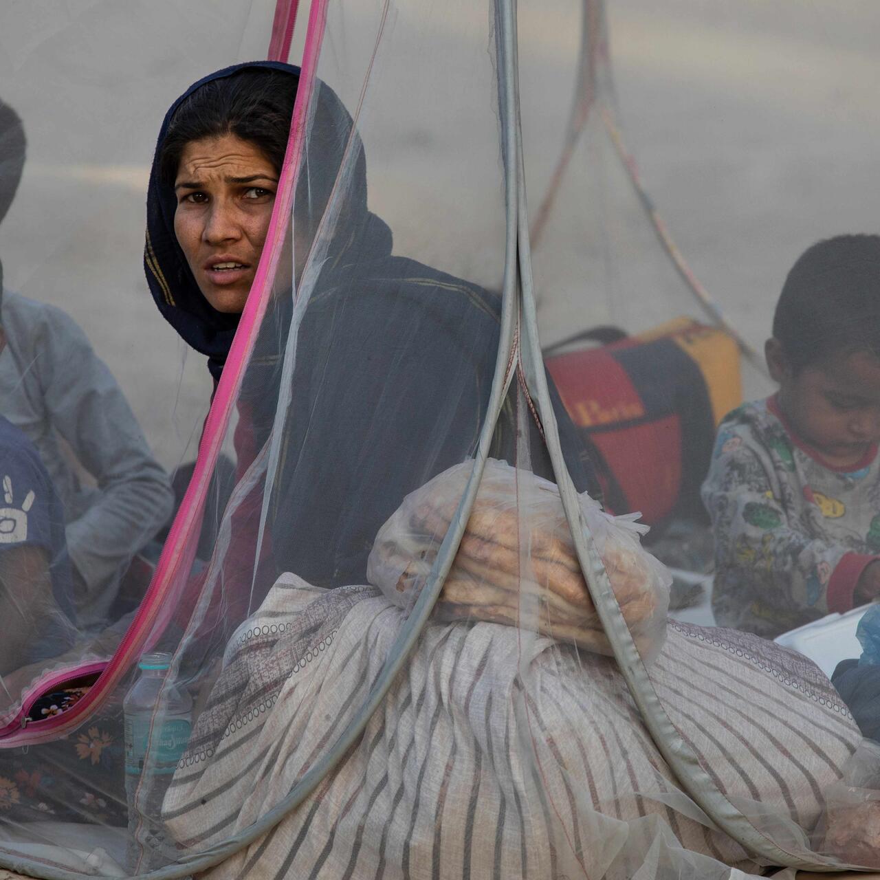 A woman sat in a tent with young children.
