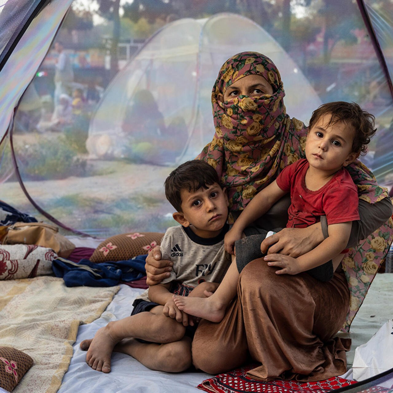 A mum with two young children sit in a tent