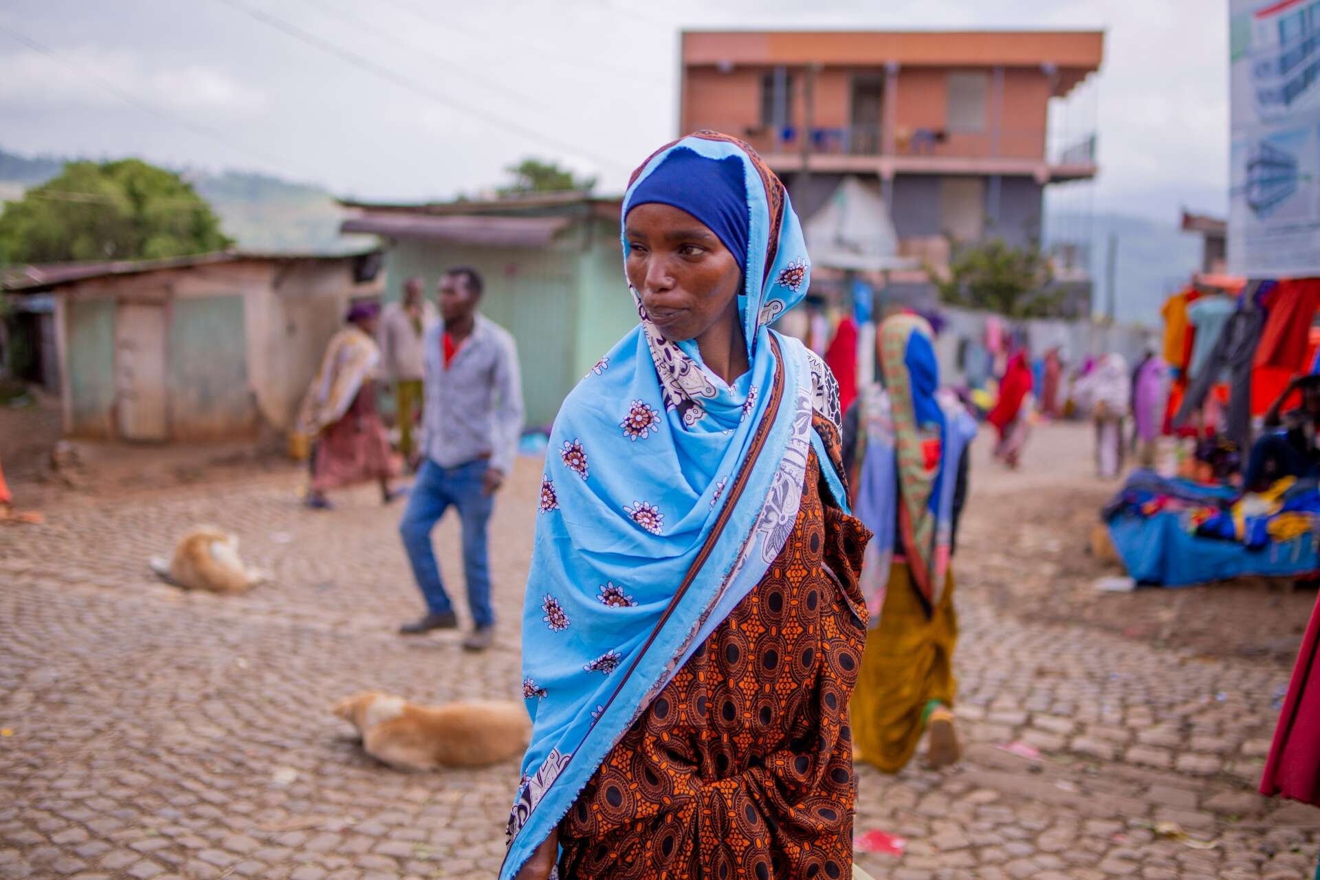 파란색 머리 스카프를 두른 한 여성이 에티오피아 데데르의 시장을 걷고 있습니다.