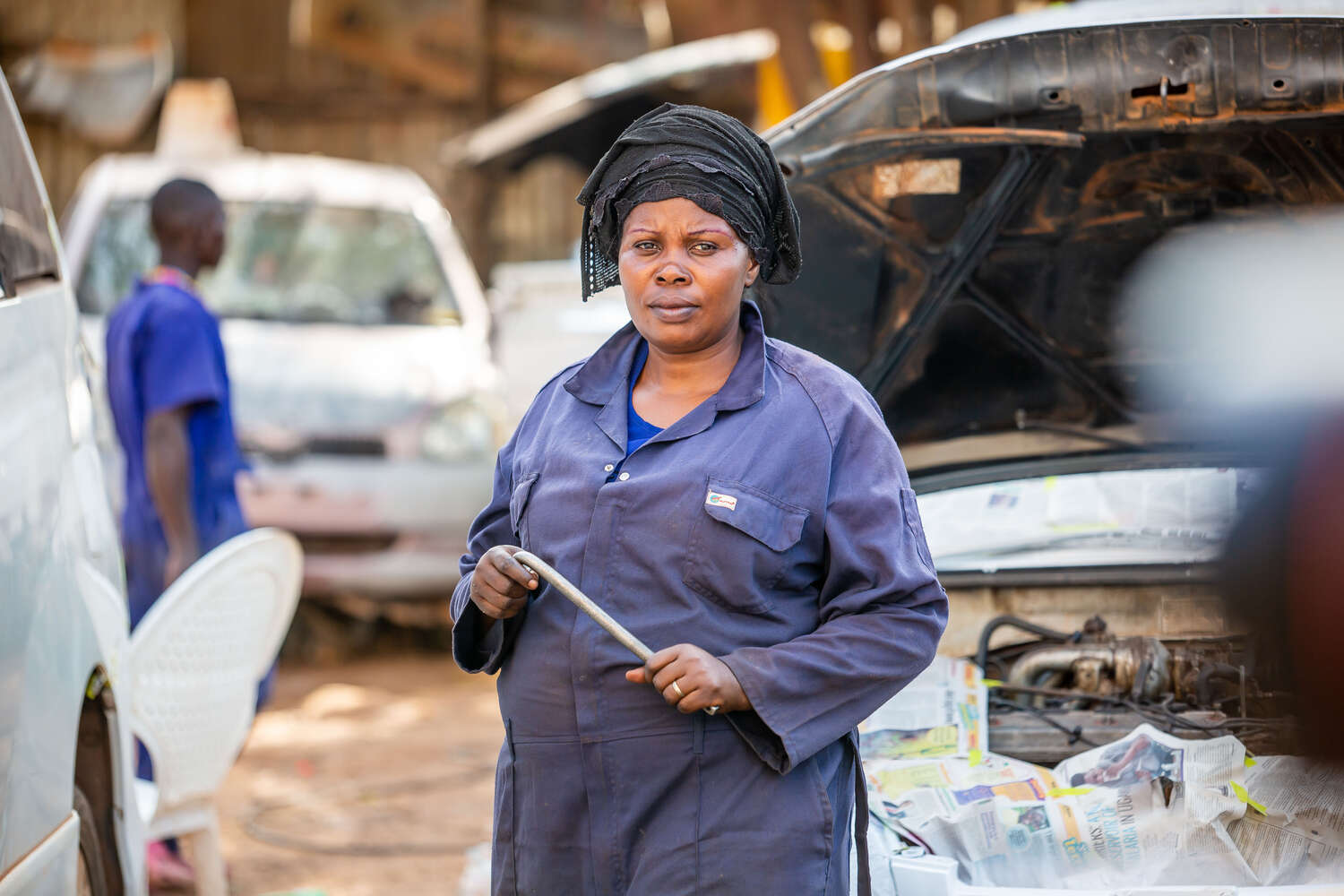 En kvinnlig mekaniker som fått stöd av RESCUE:s och IKEA:s program Re:Build står framför ett motorhuvud.