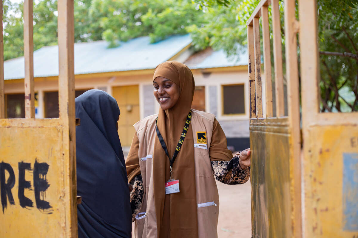 Två kvinnor i Kenya står och pratar vid en öppen grind