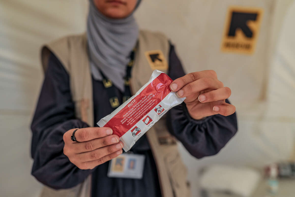 En näringsspecialist håller upp en nötkrämsklämmis som används vid behandling mot undernäring.