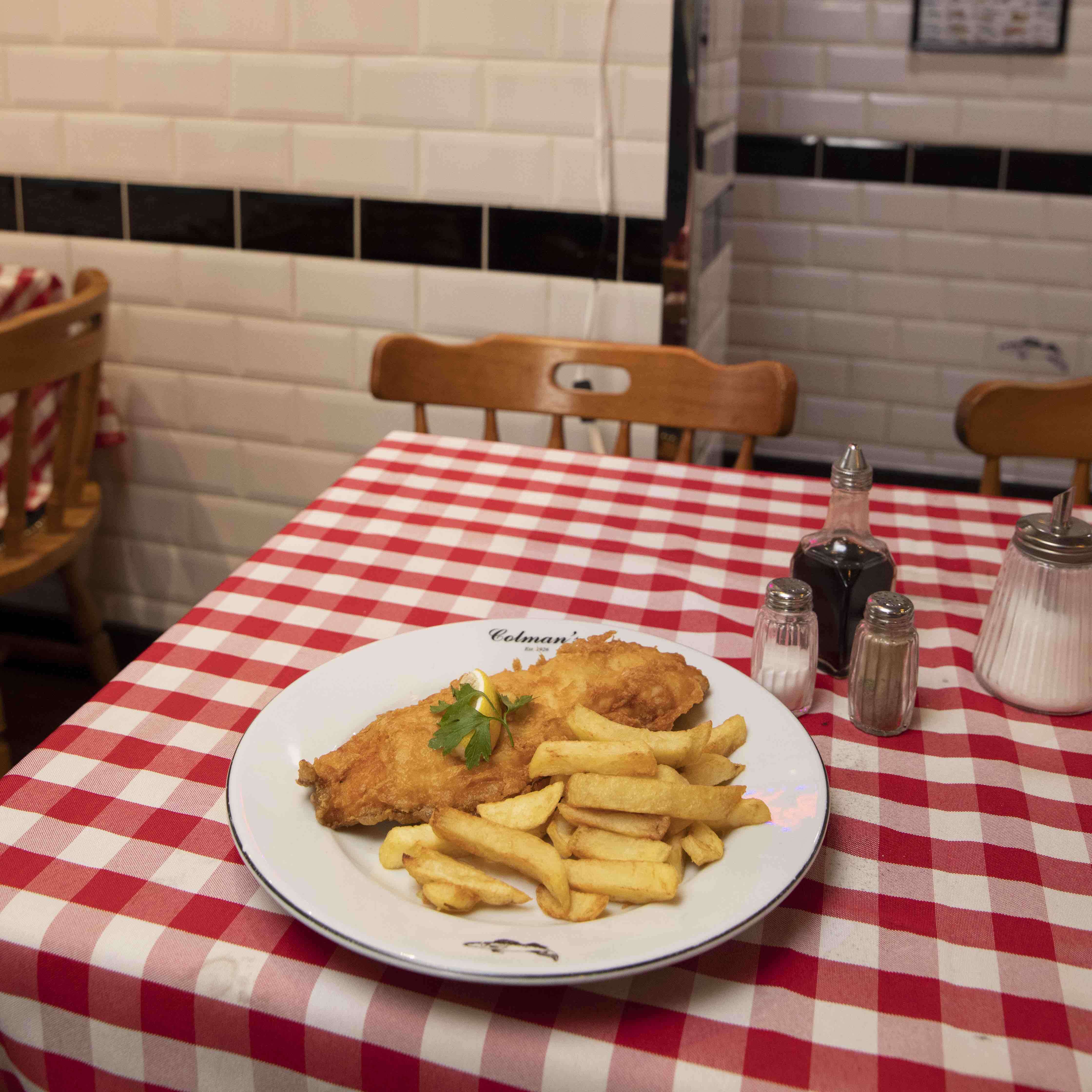 A plate of fish and chips on a checkered table cloth