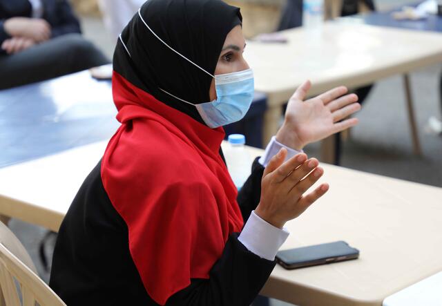 Sara sitzt an einem Tisch und redet