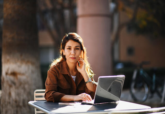 Rahila student at ASU on campus sat at a table with her laptop.