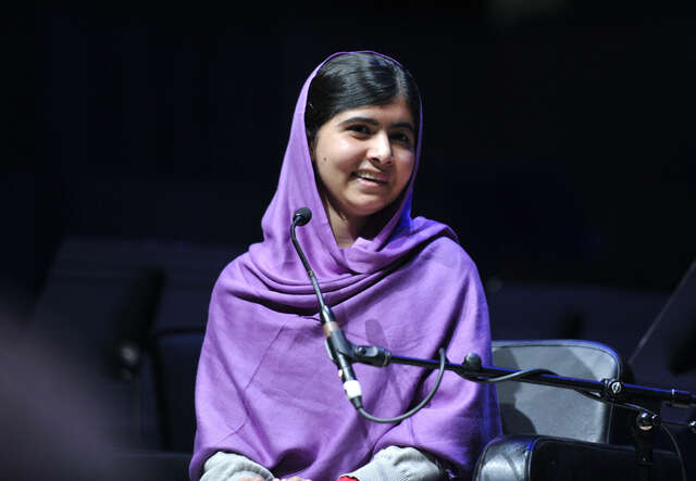 Malala Yousafzai mit lila Kopftuch spricht ins Mikrofon