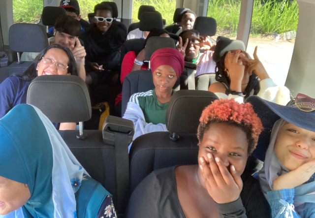 A group of summer camp students laughing in a 12 seat van.