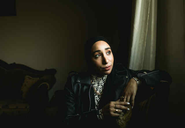 Nour sitzt auf einem Sofa und blickt aus dem Fenster.