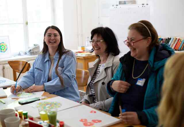 Alina, ihre Mutter Irina und ihre Freundin Switlana Lys lachen gemeinsam bei einer psychologischen Beratung für ukrainische Flüchtlinge. Die Sitzung ist Teil des Projekts "Anknüpfen", das Berufsbildungs- und Integrationsworkshops für Flüchtlinge aus der Ukraine anbietet.