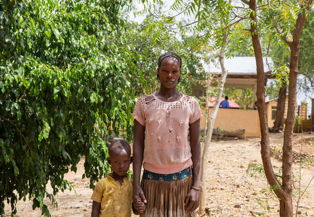 국제구조위원회 여성 고객이 자녀와 서서 카메라를 바라보고 있습니다.