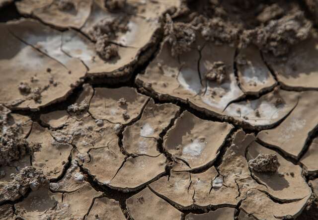  Nahaufnahme von ausgetrocknetem, rissigem Boden, der durch Trockenheit und Wassermangel geprägt ist.