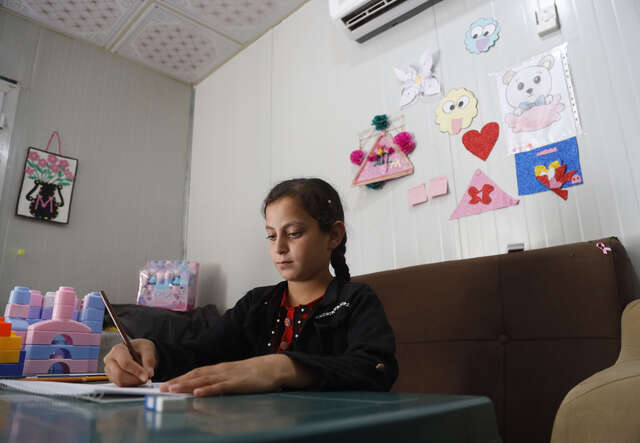 Ruba draws a painting on a piece of paper.