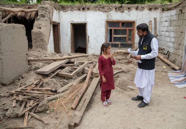 An IRC case officer speaks with a girl outside of her home in rural Afghanistan which was recently destroyed by flooding.
