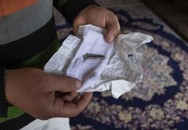 Nahaufnahme von Händen, die eine geöffnete Brieftasche mit Geldscheinen auf einem dekorativen Teppich halten.