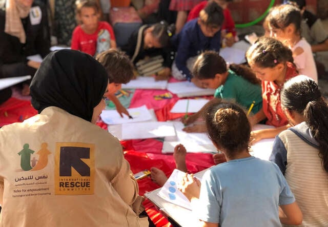 En grupp med barn sitter och ritar tillsammans med en av Nafs (som stöds av RESCUE) medarbetare i Gaza.