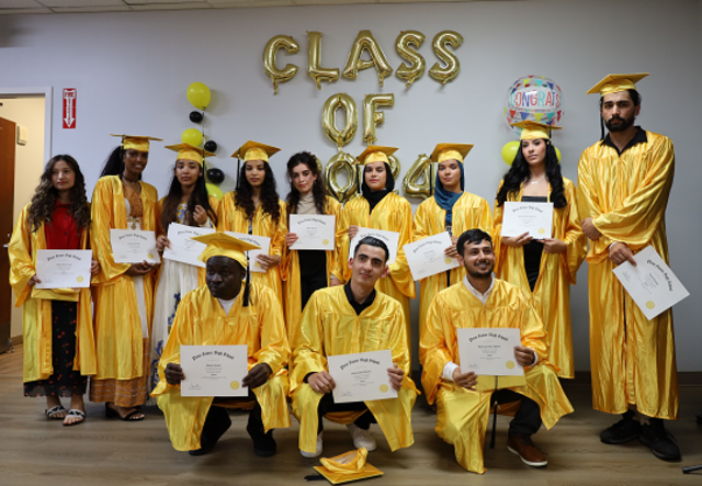 Our 2024 Class of Kickstart Graduates post for a group picture in yellow caps and gowns.