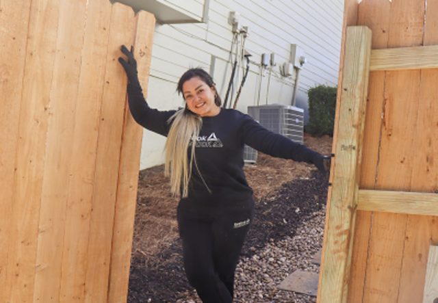 Victoria stands proudly in the opening of a gate she has built in a residential fence.