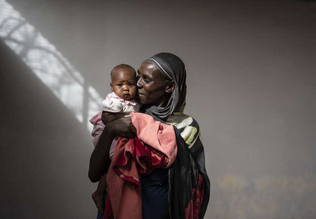 국제구조위원회의 도움을 받은 한 여성 고객이 아기에게 웃으면서 입맞추고 있습니다.
