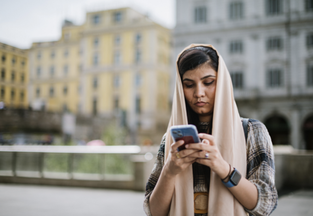 A woman in a hijab looking at her phone
