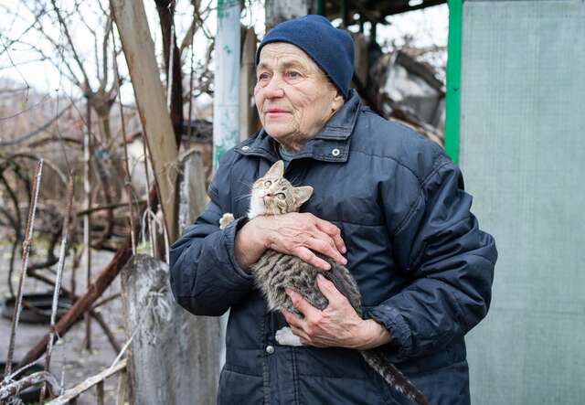 Eine ältere Frau hält ihre Hauskatze in den Armen.