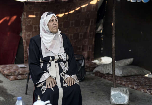 Ataf (53), sits inside her tent in Khan Younis, Gaza.