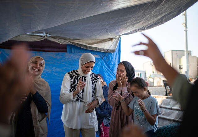 Heba and other young girls laugh and clap their hands.
